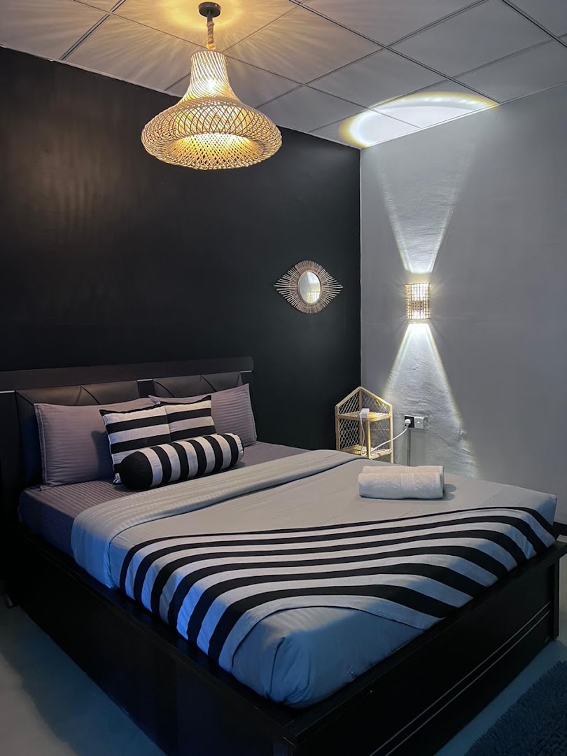 Neatly prepared room with black and white bedding and a woven lamp